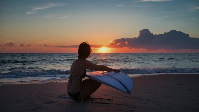 Surfer riding a wave against a beautiful sunset on a Costa Rican beach