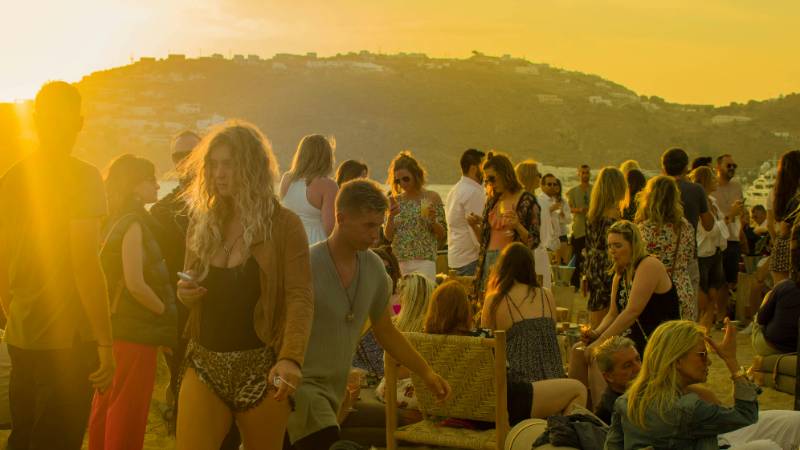 A vibrant beach club scene in Mykonos with music, cocktails, and stylish crowds